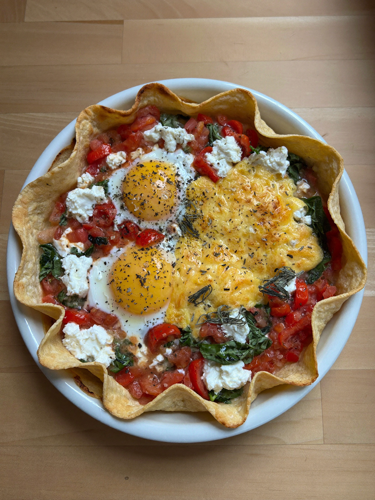 Keto tortilla egg bake in a round dish with spinach, tomatoes, cottage cheese and melted mozzarella
